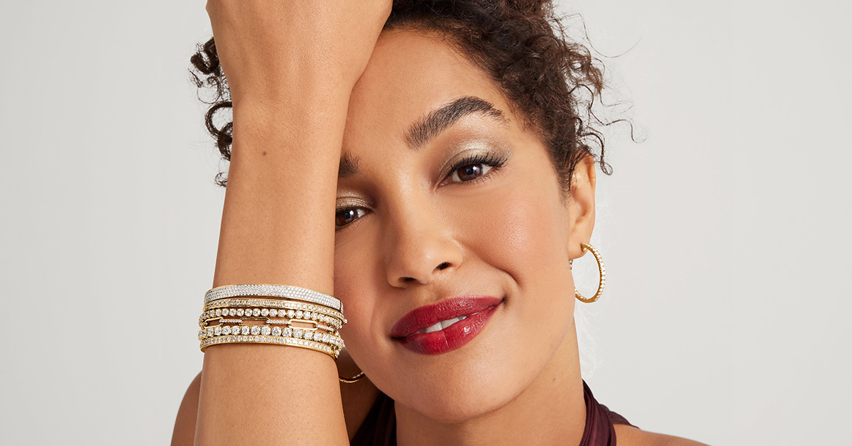Woman wearing multiple bracelets including tennis bracelets, gold bracelets and bangles.